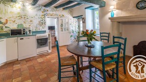 A rustic kitchen with a tiled backsplash, a microwave, and a coffee maker. - Charming house with enclosed garden near the Louet river (Denée)