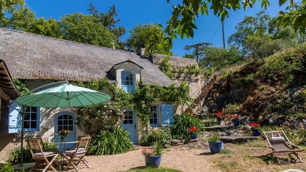 A rustic house with a thatched roof, outdoor seating, and a garden with potted plants. - Charming house with enclosed garden near the Louet river (Denée)