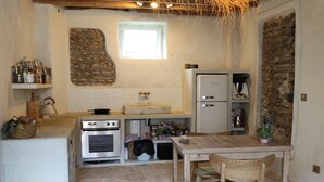 Una cocina rústica con suelo de espiga, vigas de madera en el techo, pared de piedra y una lámpara colgante.