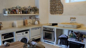 Una cocina con una mesa de madera, una pared de piedra y una ventana.