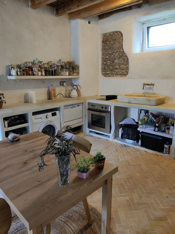 Una cocina con una mesa de madera, una pared de piedra y una ventana.