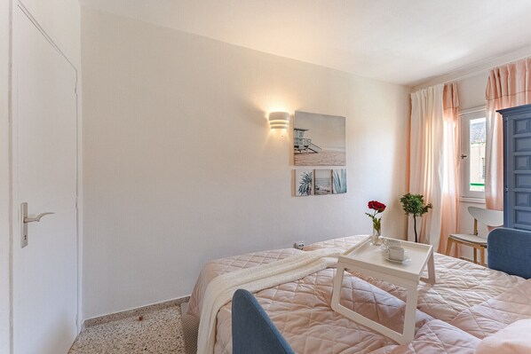 Une chambre à coucher comprenant un lit, une table de chevet et une lampe fixée au mur.