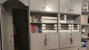 Una stanza con un'armadiatura in metallo grigio, dotata di diversi cassetti e ripiani, che contiene libri e oggetti decorativi.