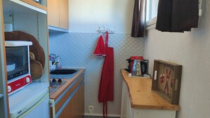 Una cucina compatta con un fornello, un lavello e un piccolo bancone.