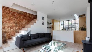 A modern living room with a grey sofa, glass coffee table, and a brick wall. - The Brickworks, by Veeve (London)