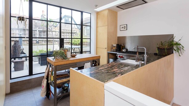 A modern kitchen with large windows, a wooden island, and a view of the outside. - The Brickworks, by Veeve (London)