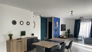 Una cucina moderna con zona pranzo, caratterizzata da un tavolo di legno, sedie e una parete di colore blu.