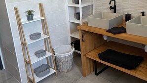Un bagno moderno con un grande specchio, due lavabi e scaffali a muro.