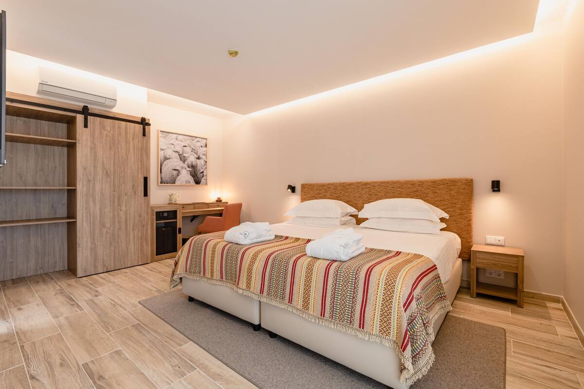 Una habitación de hotel moderna con una cama grande, un escritorio y un armario.
