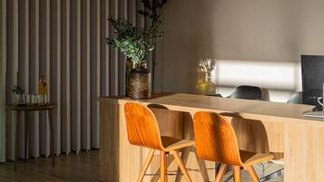 A modern kitchen with a wooden island, two chairs, a hanging light, and a striped wall.