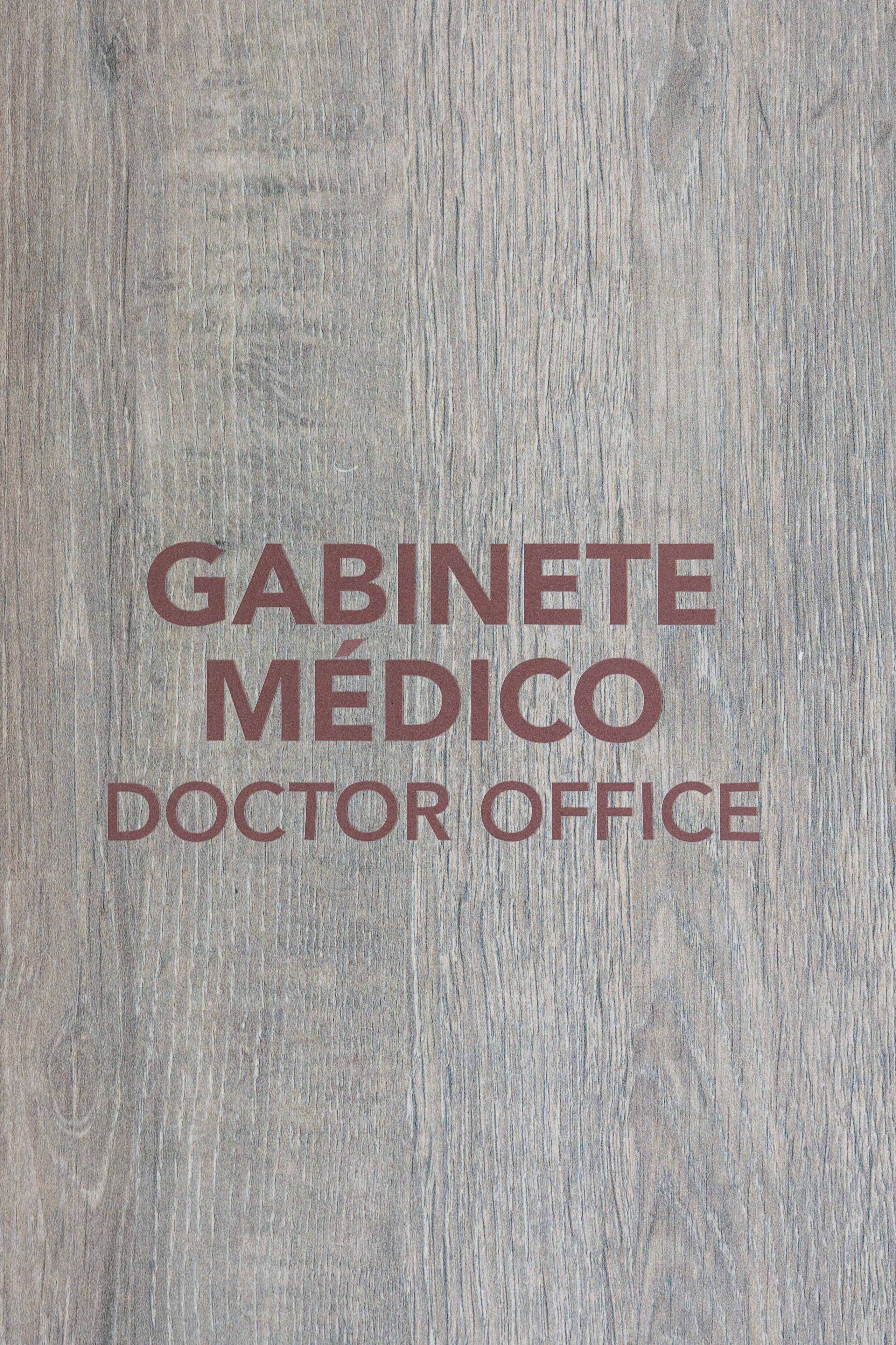 A wooden textured surface with the text "GABINETE MÉDICO DOCTOR OFFICE".