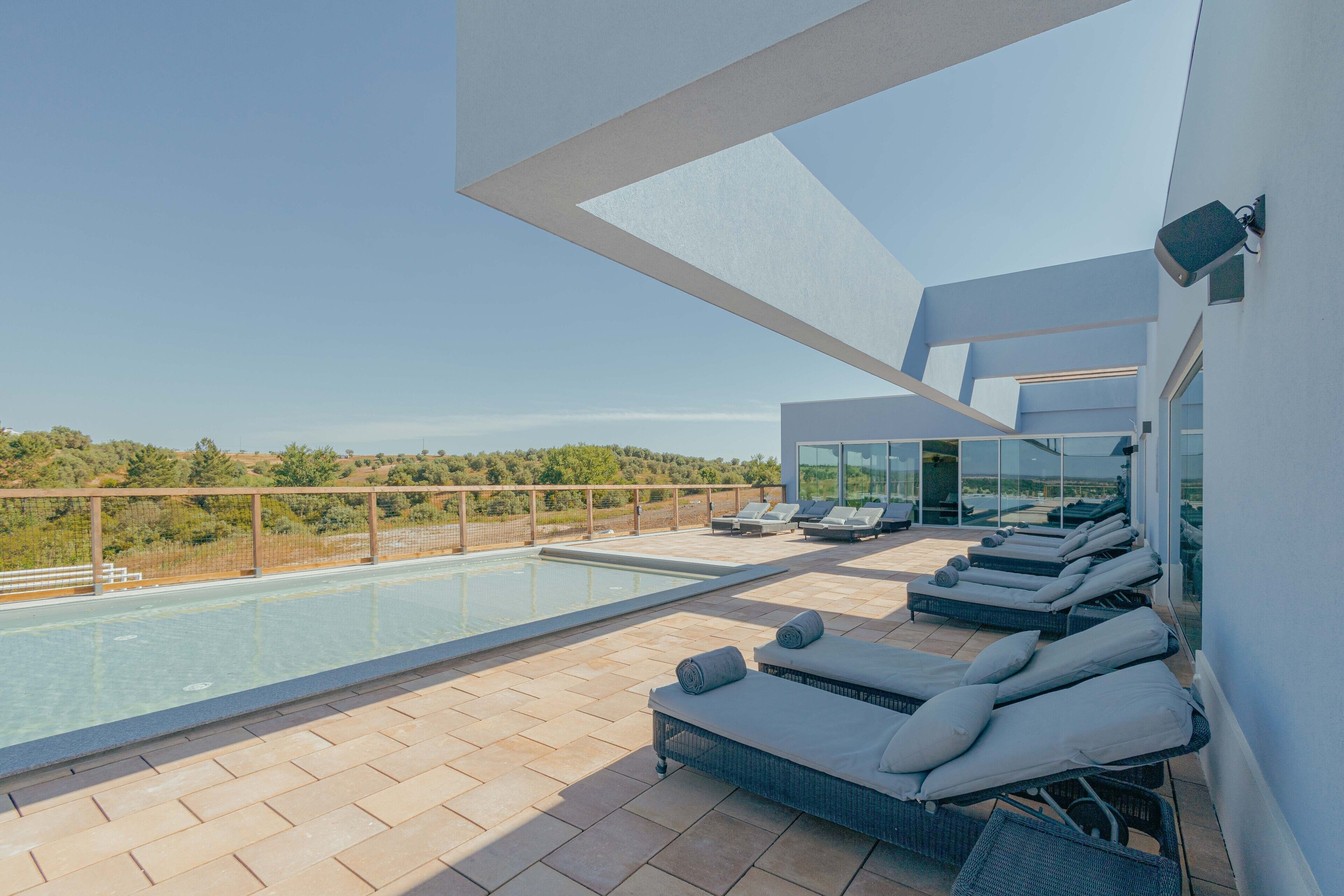 A rooftop pool area with lounge chairs and a clear view of the surrounding landscape.