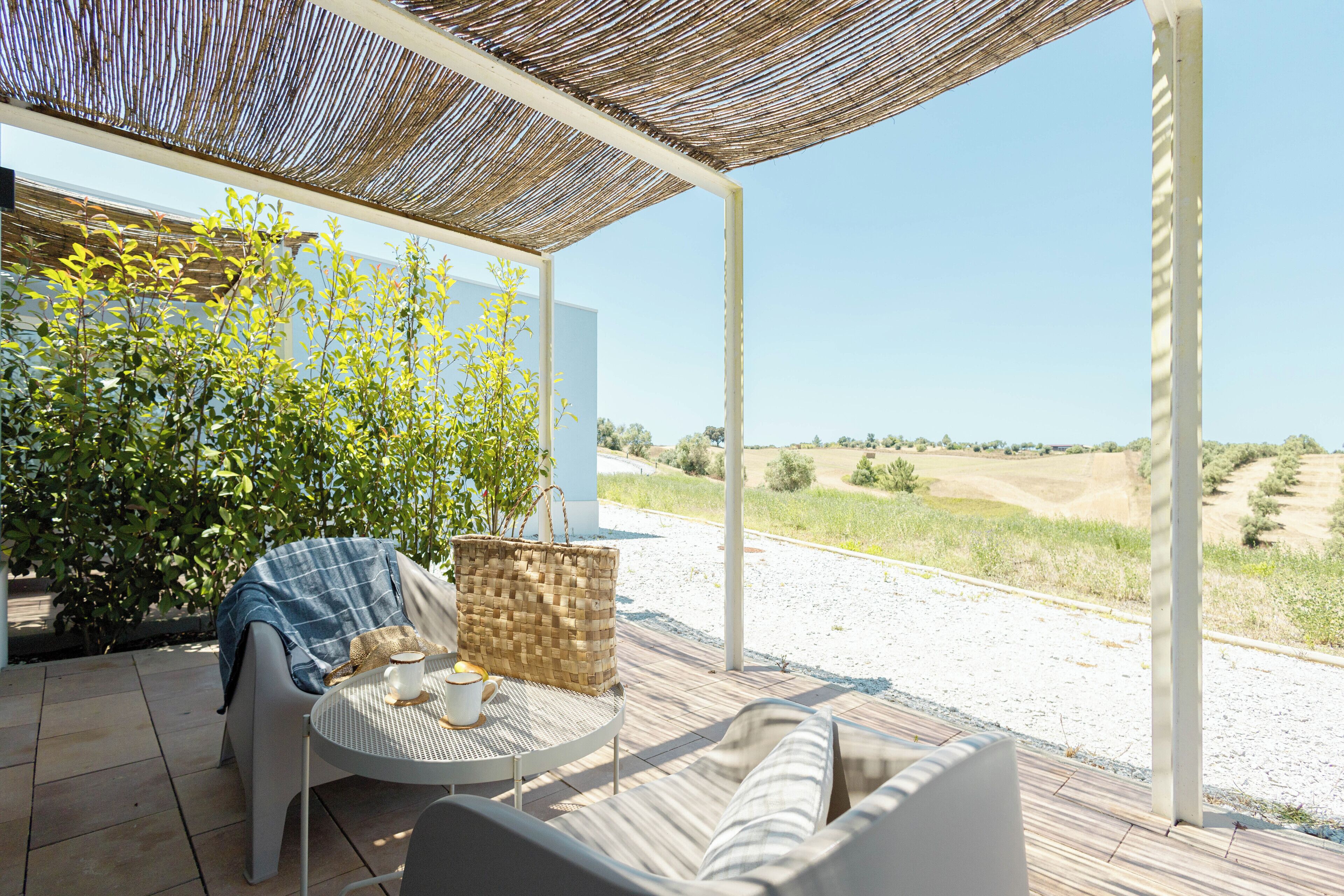 Un patio al aire libre con una mesa de mimbre, un sofá acolchado y una cesta de mimbre.