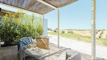 Un patio al aire libre con una mesa de mimbre, un sofá acolchado y una cesta de mimbre.