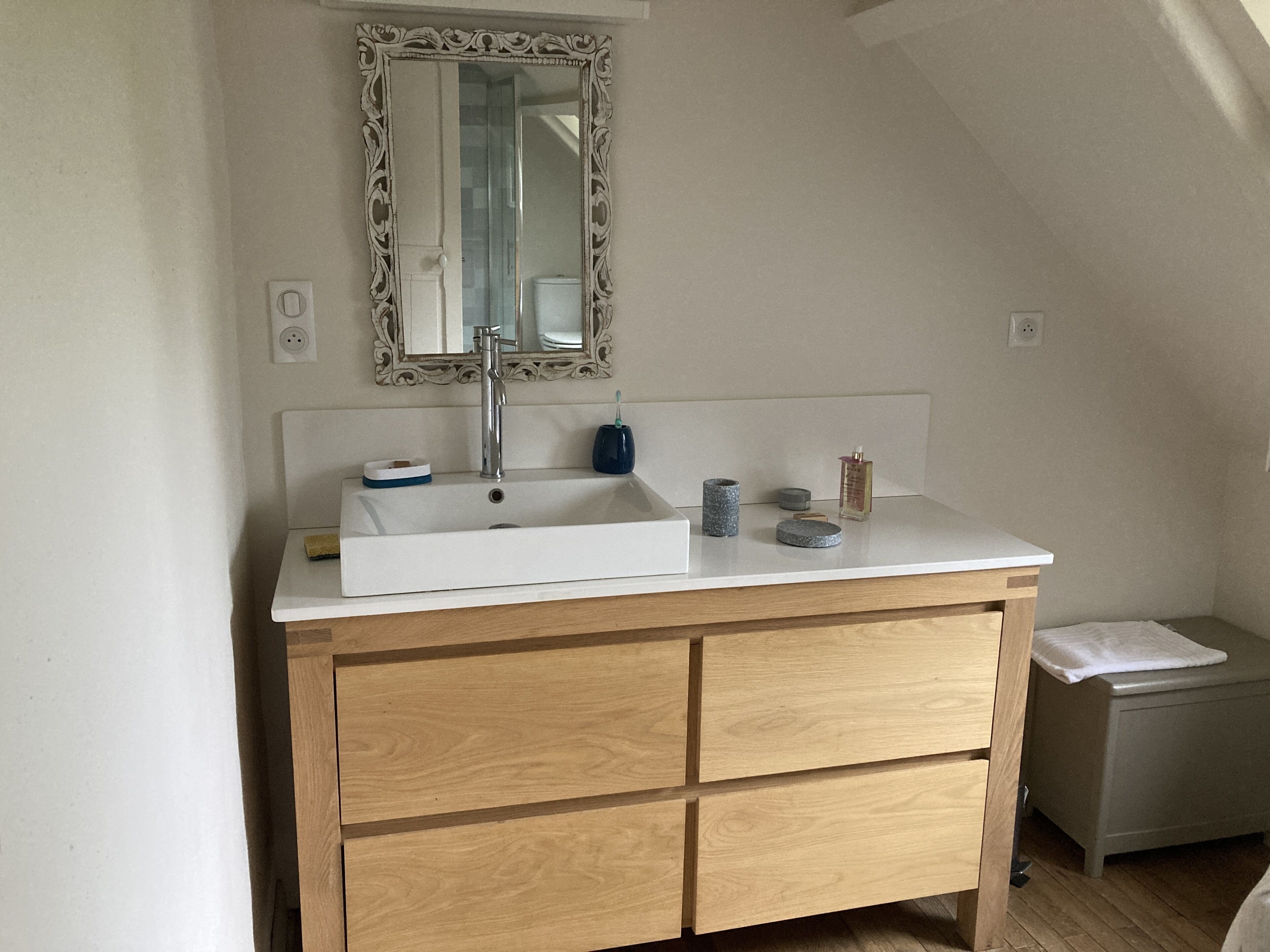 Une salle de bain avec un lavabo blanc, un meuble-lavabo en bois et un miroir au-dessus du lavabo.
