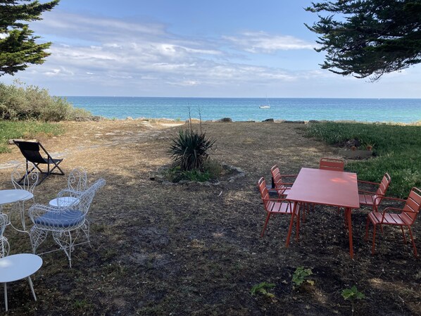 Un espace extérieur aménagé avec une table et des chaises, un petit jardin et une vue sur la mer.