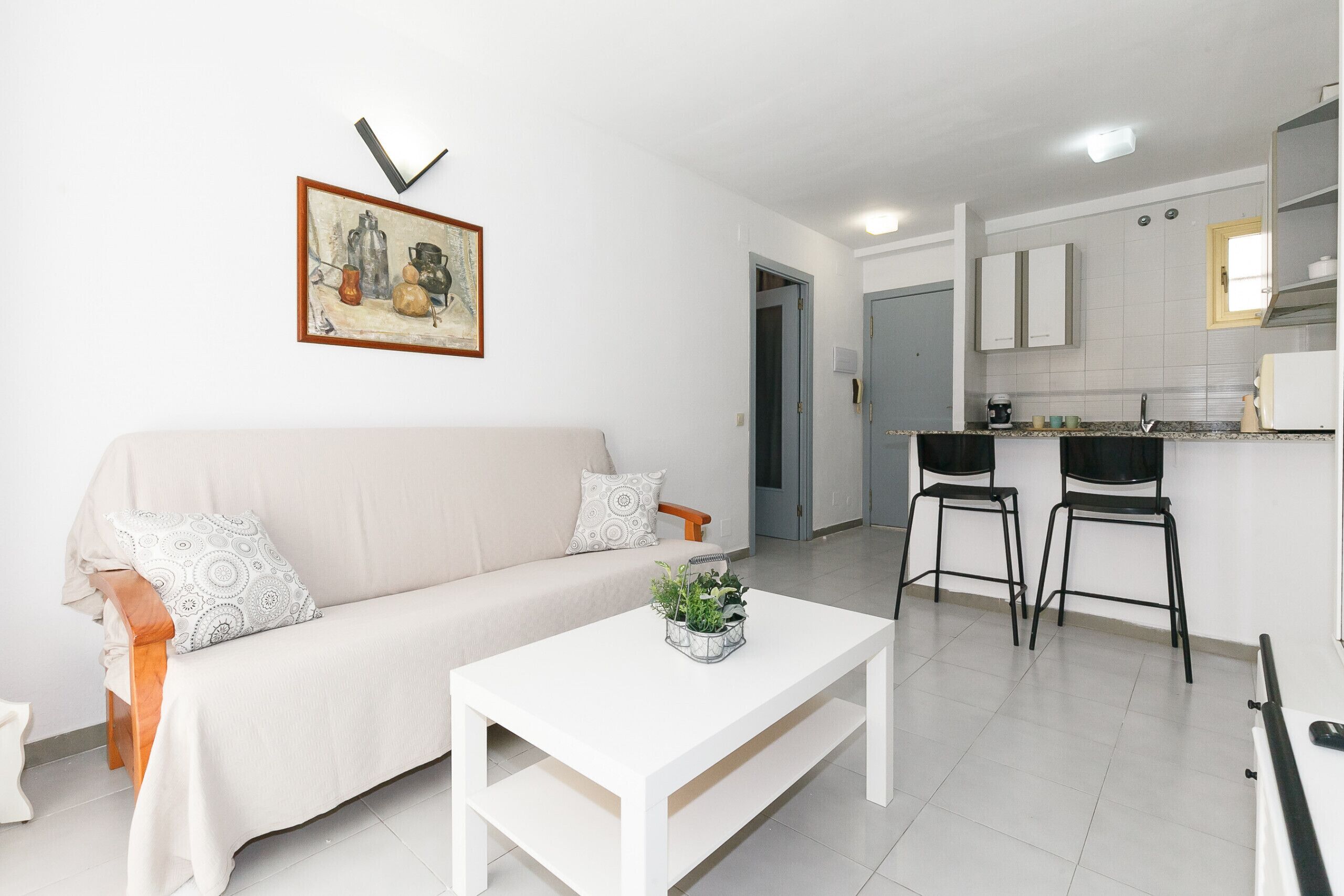 Un salon moderne avec un canapé, une table basse et un tableau accroché au mur.