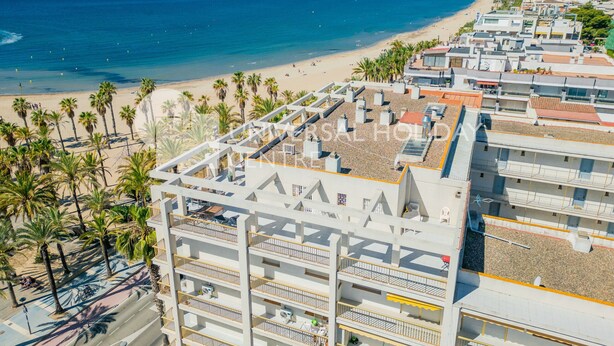 Un hotel frente al mar con varios balcones, vista a la playa y una terraza en la azotea.