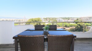 Un balcon avec une table et des chaises, donnant sur un paysage urbain.