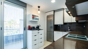Een moderne keuken met een schuifdeur, een ingebouwde koffiezetapparaat en een roestvrijstalen koelkast.
