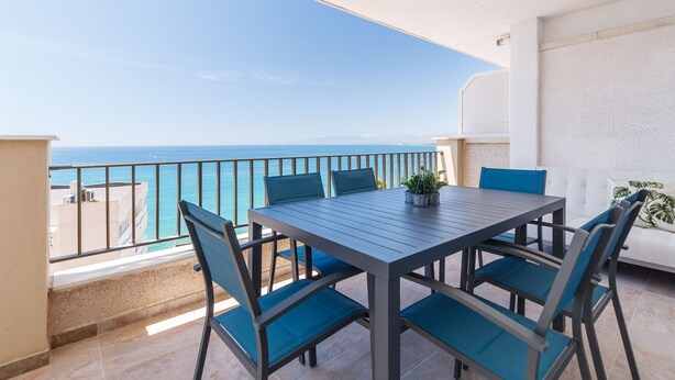 Ein Balkon mit Tisch und Stühlen mit Blick aufs Meer.