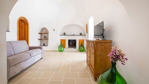 A living room with a sofa, a cabinet, a fireplace, and a TV. - GuestHost - Trullo Bella Vista x4 with patio and parking space (Fasano)