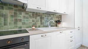 A kitchen with white cabinets, a green tiled backsplash, a sink, and a stove. - GuestHost - Trullo Bella Vista x4 with patio and parking space (Fasano)