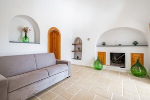 A living room with a sofa, a fireplace, and green vases on shelves.