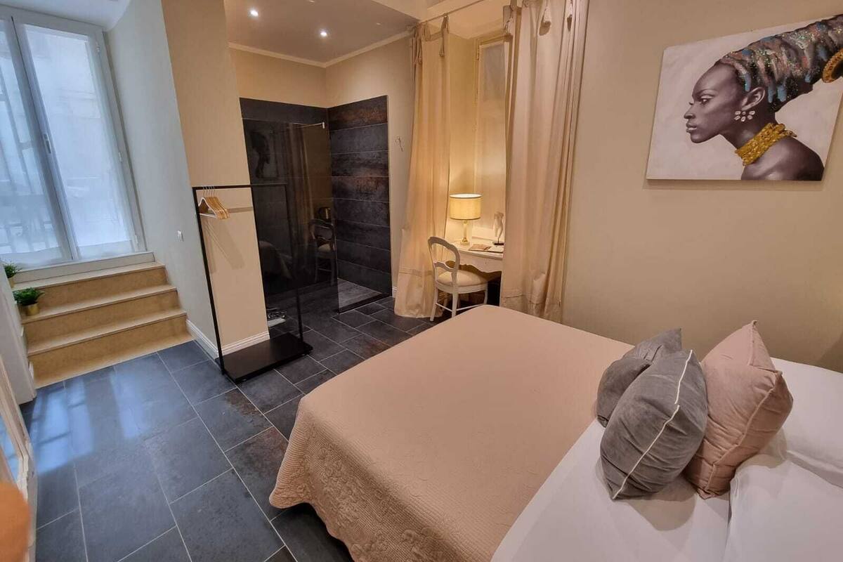 Una habitación de hotel moderna con una cama grande, zona de ducha y escritorio con lámpara.