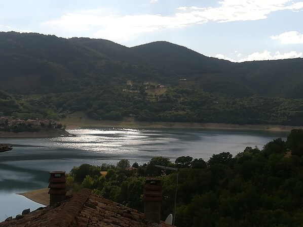 A view of a river with mountains in the background and a building with a chimney in the foreground.