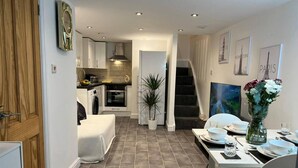 A compact living space with a kitchenette, a dining area, and a staircase leading to an upper level. - Jacuzzi Spa! Stunning Entire Guest House - Netflix (Derby)