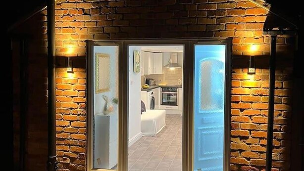 A brick building with a large glass door and two wall-mounted lights. - Jacuzzi Spa! Stunning Entire Guest House - Netflix (Derby)