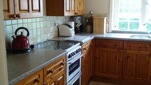 A kitchen with wooden cabinets, a stainless steel kettle, a toaster, and a bread box.