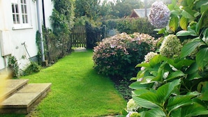 A well-maintained garden with a lawn, a wooden fence, and various flowering plants.