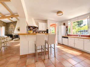 Een keuken met een stenen muur, een betegelde vloer en een raam met uitzicht op groen.