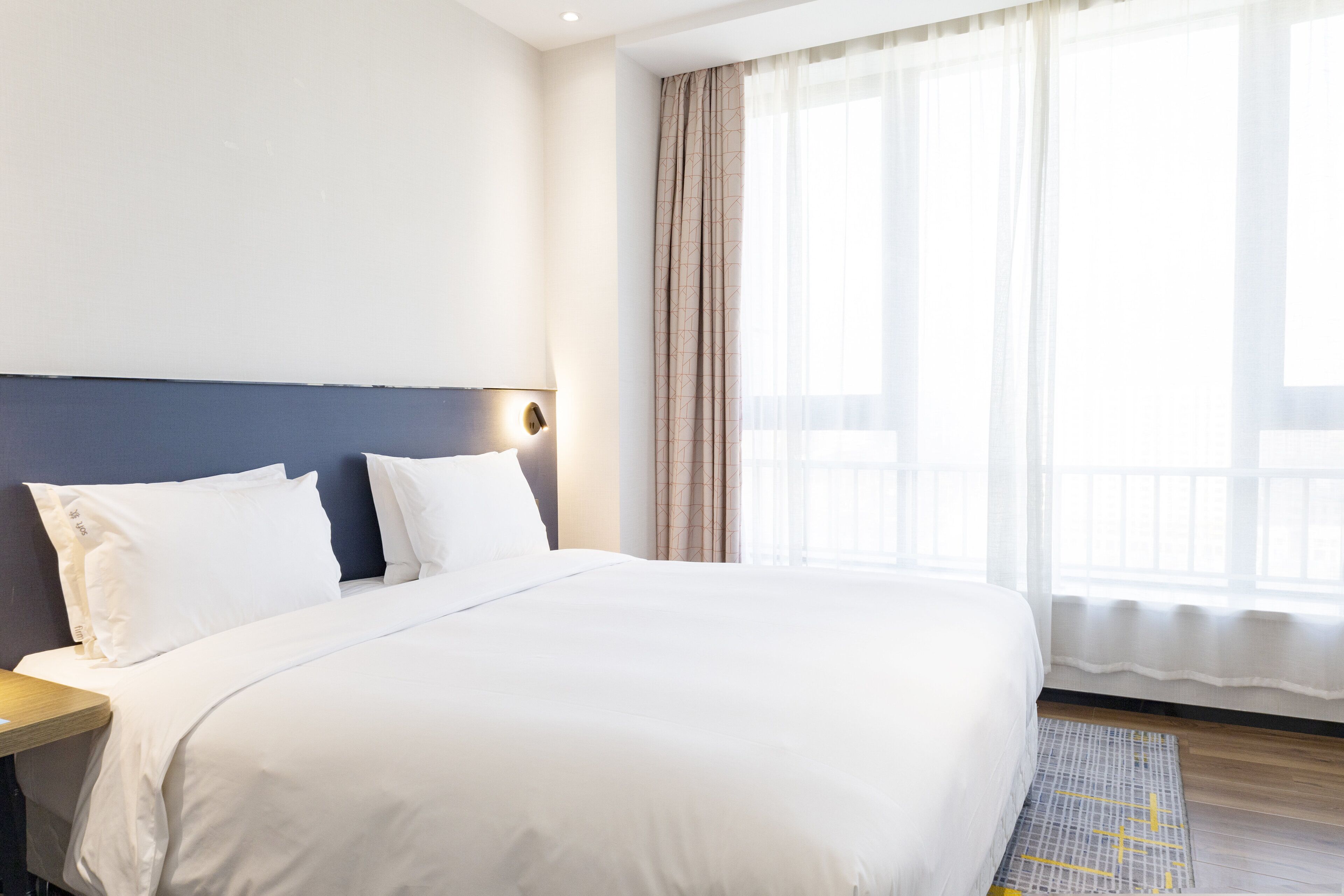 A neatly made bed with white linens in a hotel room.