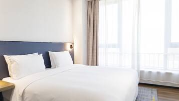 A neatly made bed with white linens in a hotel room.