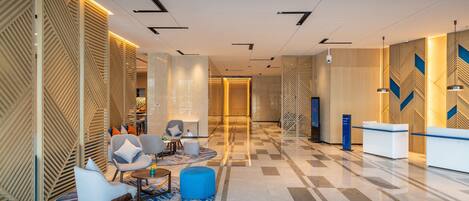 A modern lobby with a reception desk, seating area, and a check-in counter.