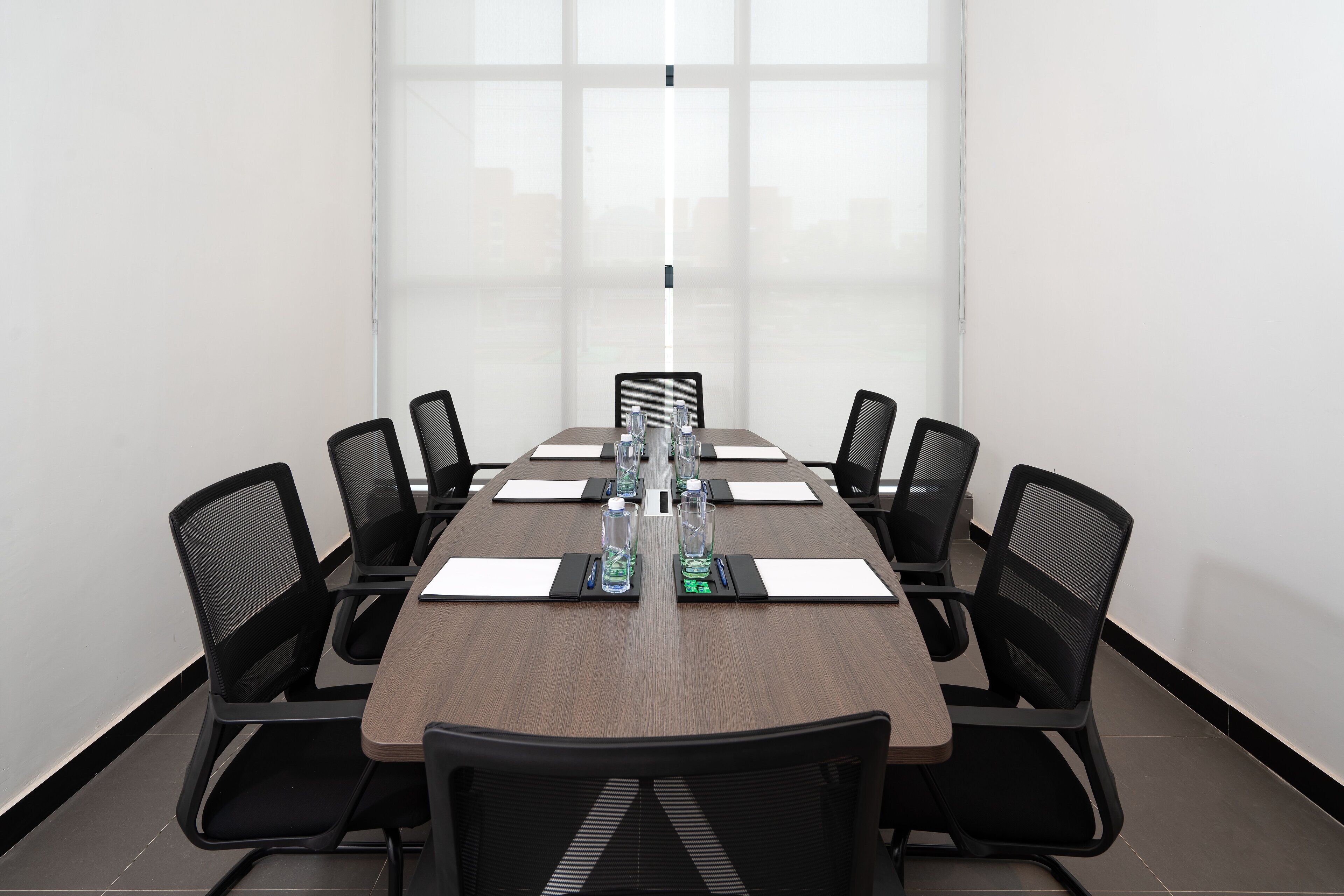 A conference room with a long table, black chairs, and water bottles.