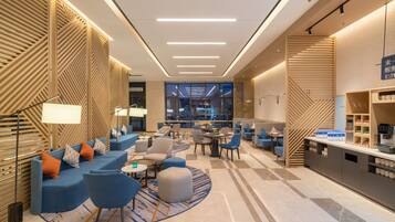 Una hall d'albergo moderna con zone relax, un bar e vista sulla città.