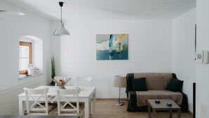 A modern living room with a dining area, a sofa, a coffee table, and a painting on the wall.