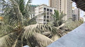 Vista de um edifício residencial com vários andares e varandas, cercado por palmeiras.