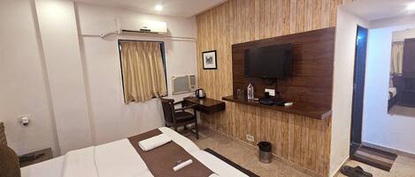A hotel room with a bed, a desk, a television, and a wooden wall panel.