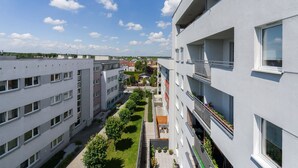 Un edificio residencial de varios pisos con balcones, un patio interior y cielo despejado.