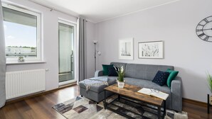Una sala moderna con un sofá gris, una mesa de centro de madera y una alfombra estampada.
