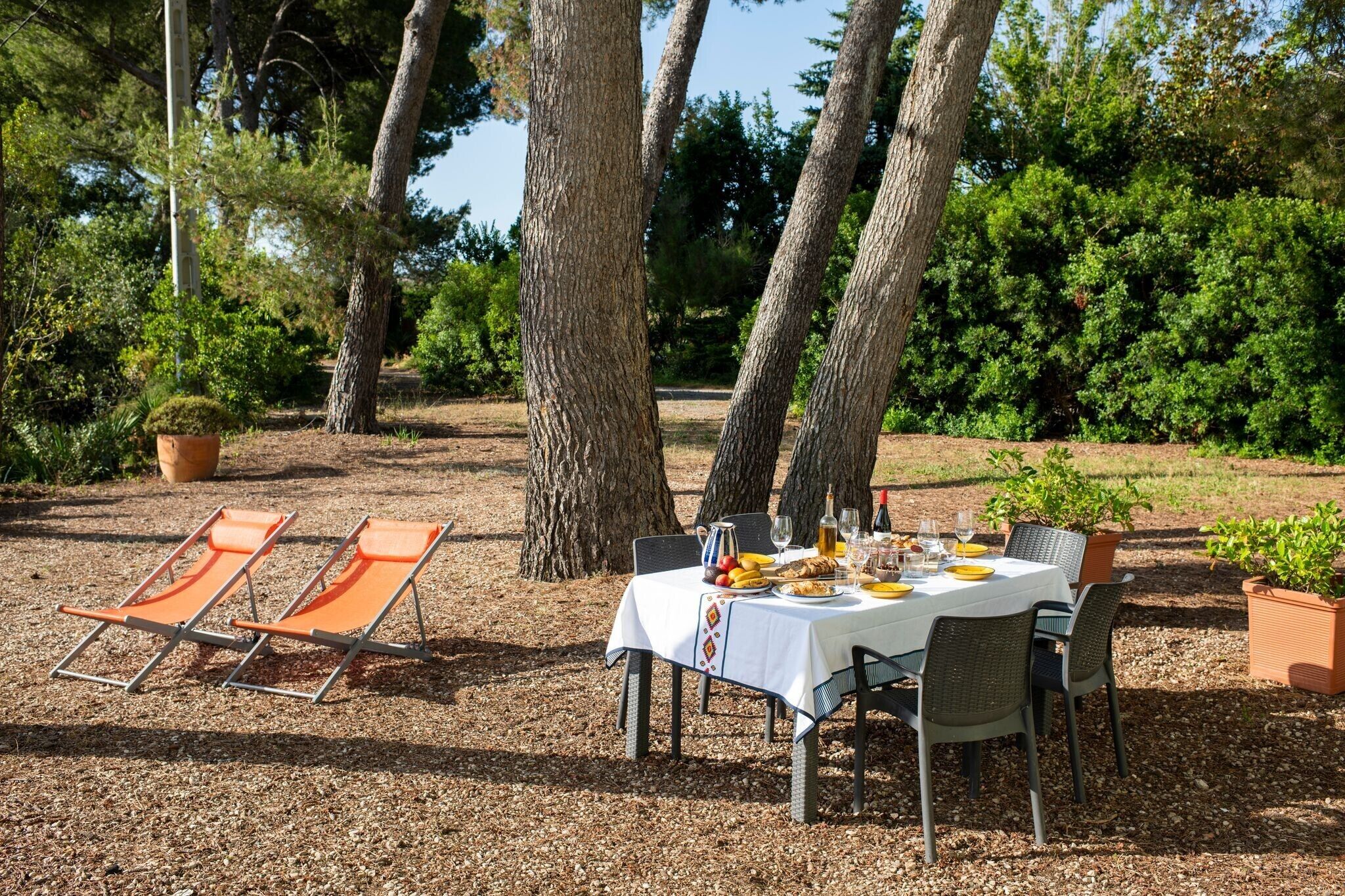Un área de comedor al aire libre con una mesa preparada para cuatro personas, rodeada de sillas y dos sillones.