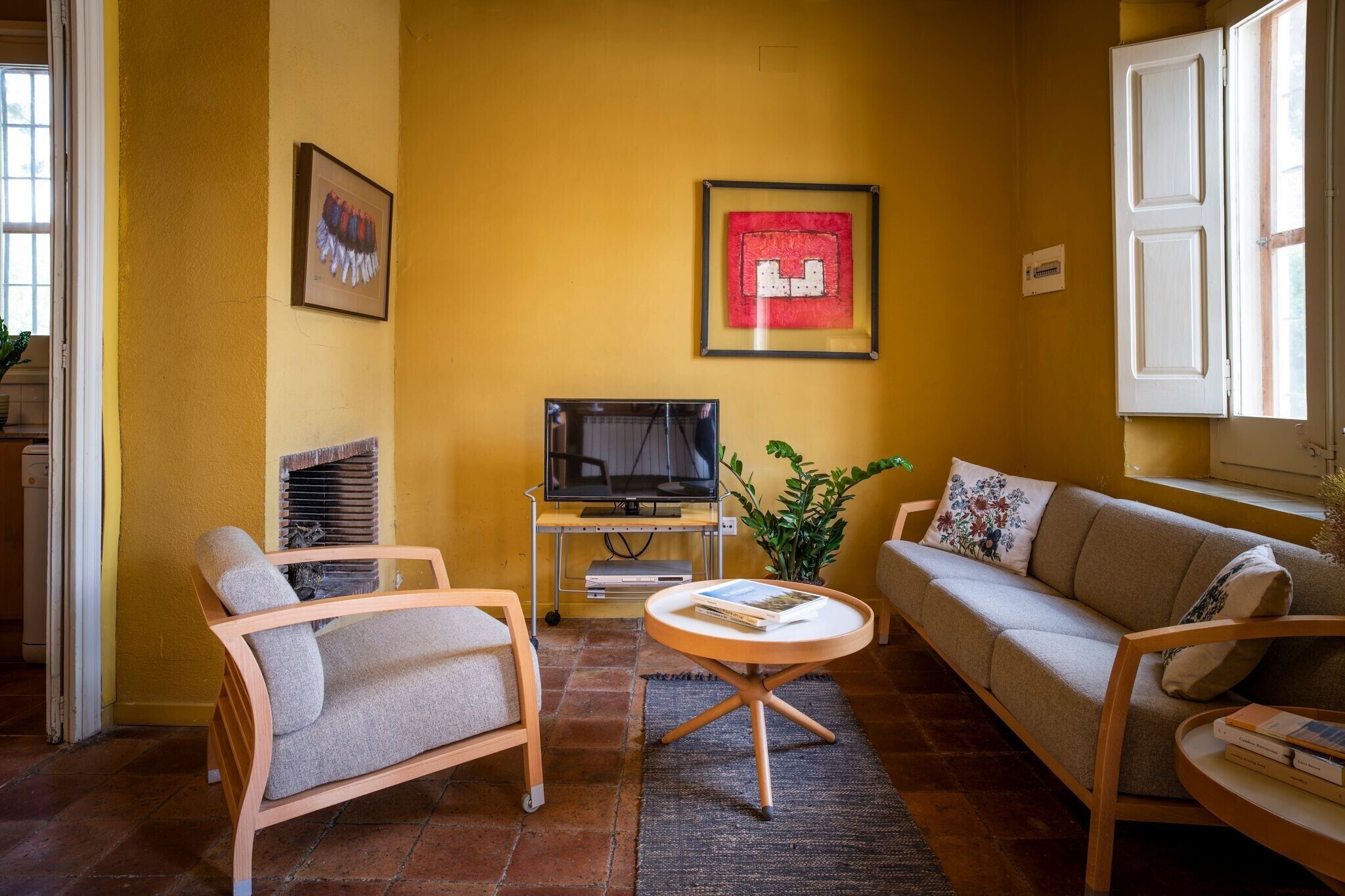 A living room with a sofa, armchair, TV, and a small table.