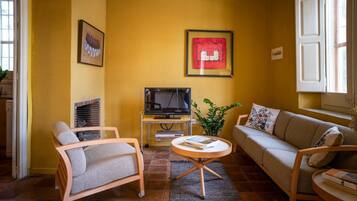 A living room with a sofa, armchair, TV, and a small table.
