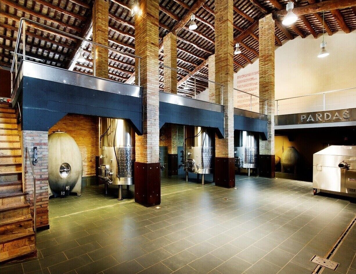 Un ampio interno in stile industriale, con pareti in mattoni a vista, travi metalliche e attrezzature in acciaio inossidabile.