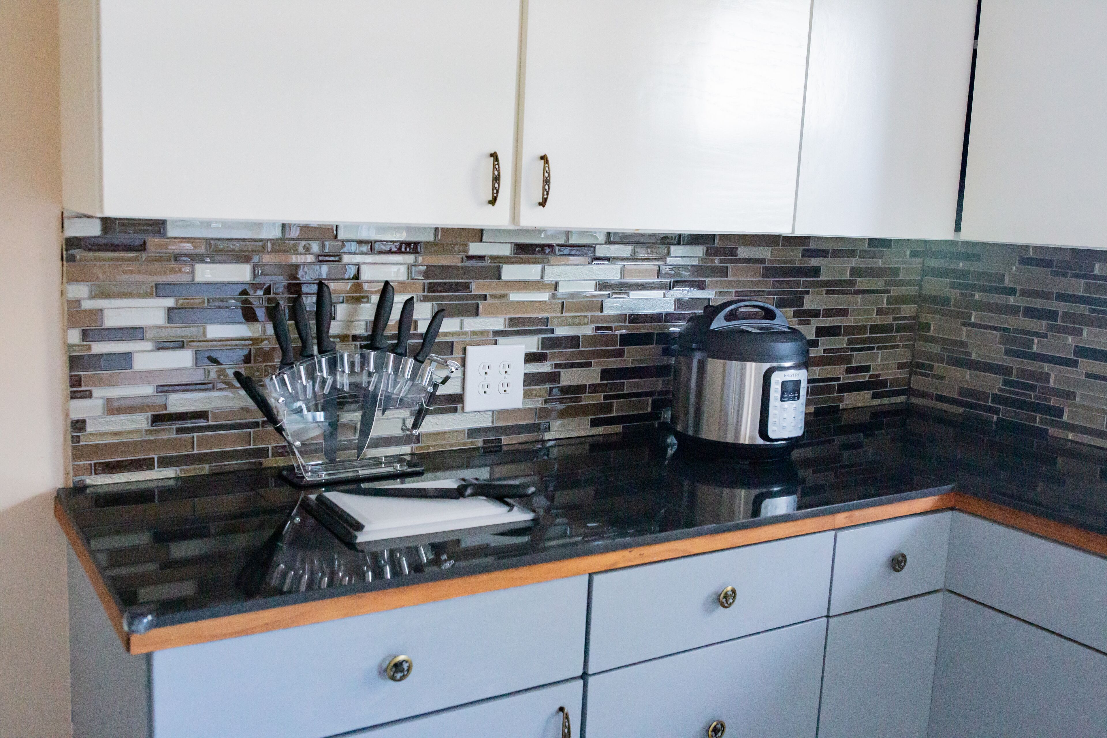 A kitchen with a black countertop, a coffee maker, and a knife block.